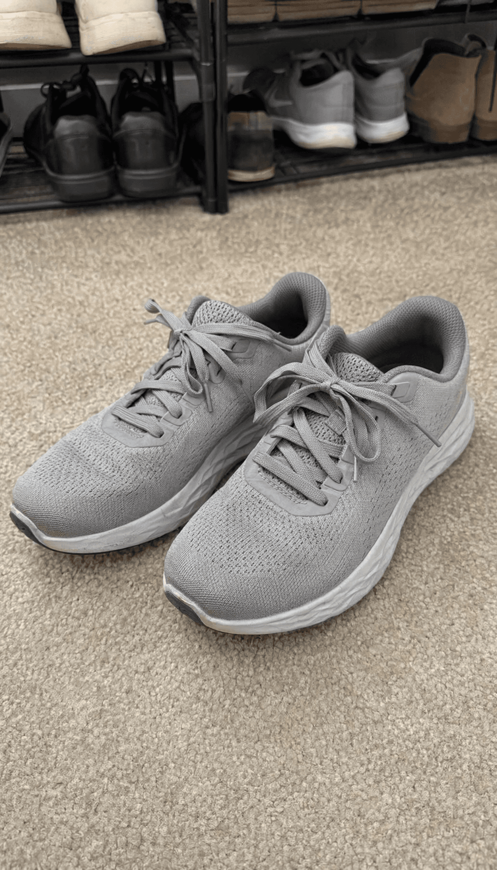 Pair of gray sneakers photographed near a shoe rack before cleanup